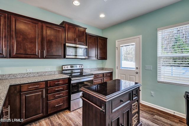 kitchen with dark brown cabinets, baseboards, stainless steel appliances, and wood finished floors