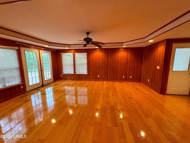 interior space with french doors, ceiling fan, and wooden walls