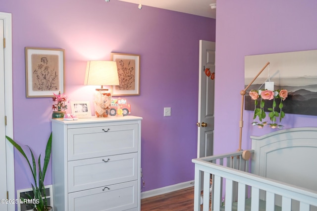 bedroom featuring a nursery area and dark hardwood / wood-style flooring