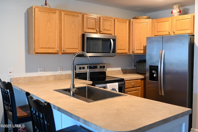 kitchen with sink, a kitchen bar, kitchen peninsula, and appliances with stainless steel finishes