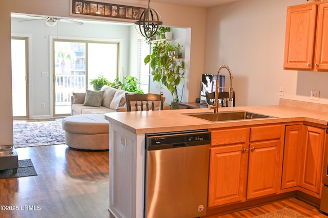 kitchen featuring hardwood / wood-style floors, pendant lighting, dishwasher, sink, and kitchen peninsula