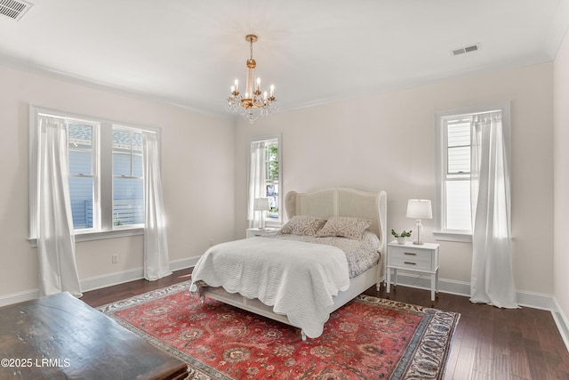 bedroom with baseboards, dark wood-style flooring, visible vents, and an inviting chandelier