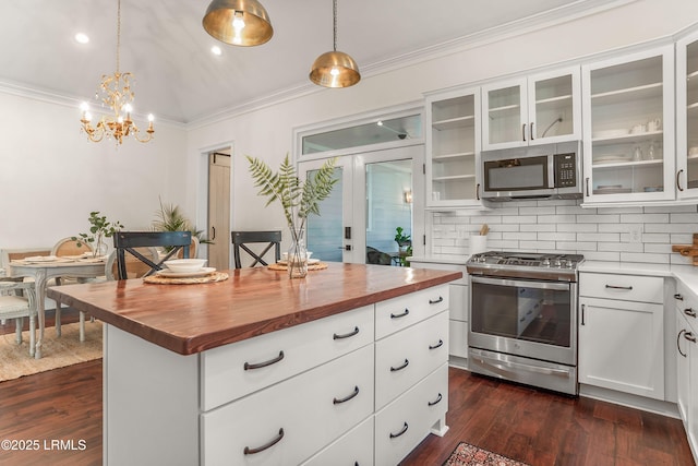 kitchen with hanging light fixtures, wood counters, appliances with stainless steel finishes, and a center island