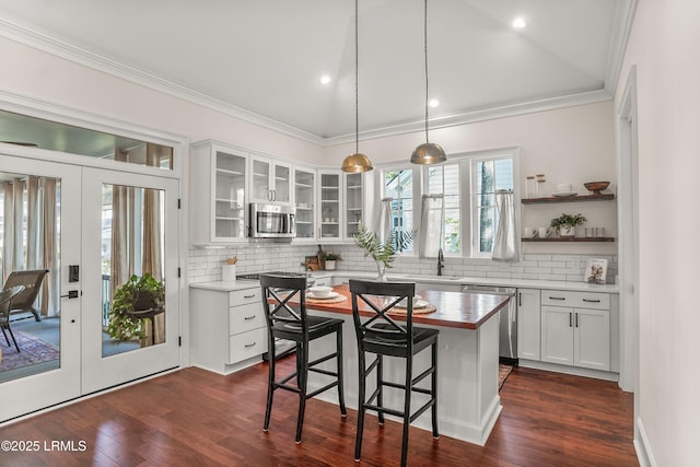 kitchen with a kitchen island, glass insert cabinets, appliances with stainless steel finishes, french doors, and white cabinetry