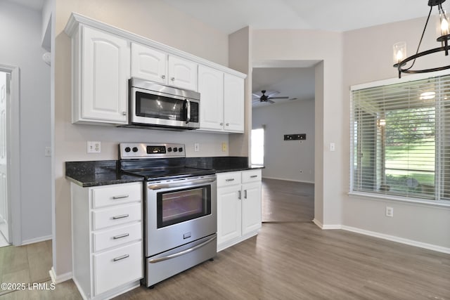 22 Purry Cir, Bluffton, SC 29909 - kitchen with stainless steel appliances, white cabinets, wood finished floors, a ceiling fan, and dark stone countertops