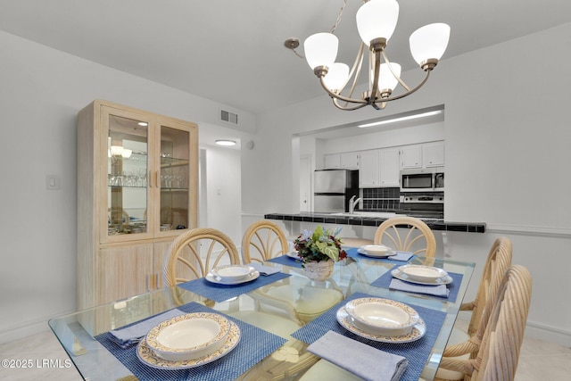 tiled dining space with sink and a notable chandelier