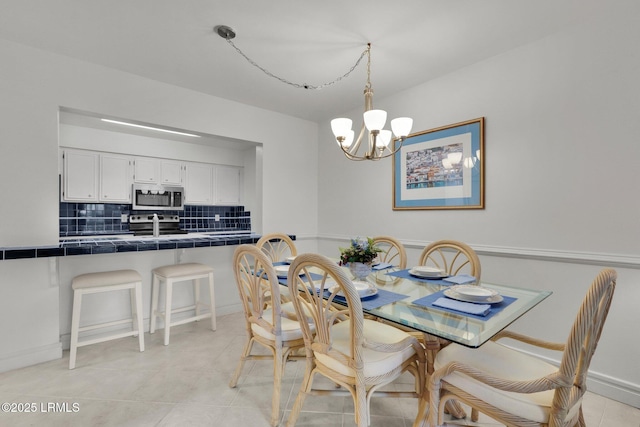 dining area with sink, light tile patterned floors, and a chandelier