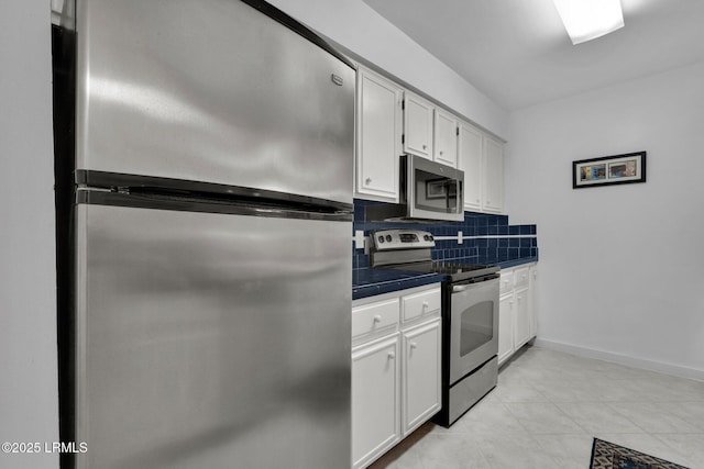 kitchen featuring white cabinetry, appliances with stainless steel finishes, tile counters, and decorative backsplash