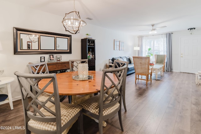 dining space with ceiling fan with notable chandelier and hardwood / wood-style floors