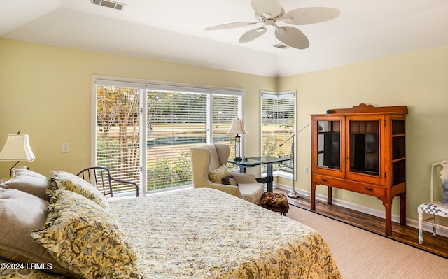 bedroom with vaulted ceiling, hardwood / wood-style flooring, access to exterior, ceiling fan, and a tray ceiling