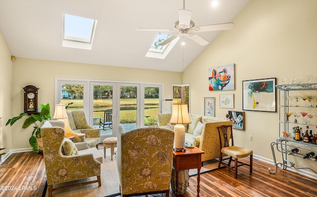 living area with dark wood-type flooring, vaulted ceiling with skylight, and ceiling fan