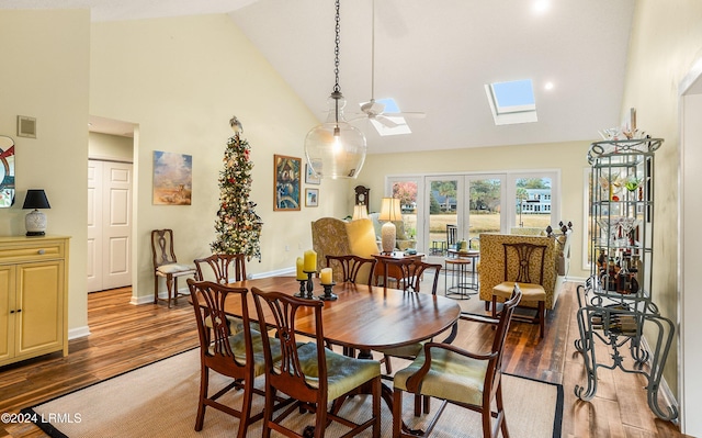 dining area featuring dark wood-type flooring, a skylight, high vaulted ceiling, and ceiling fan