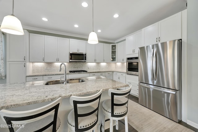 kitchen featuring white cabinetry, appliances with stainless steel finishes, sink, and decorative light fixtures