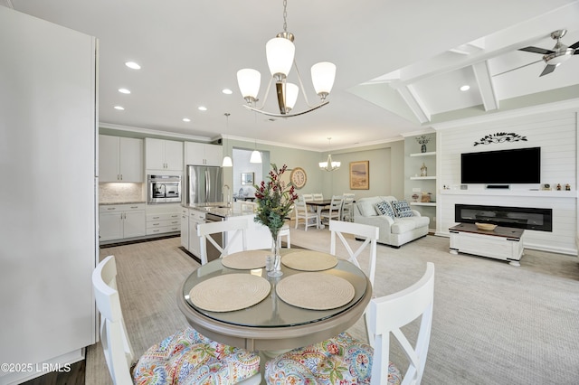 dining space with crown molding, sink, ceiling fan with notable chandelier, and light carpet