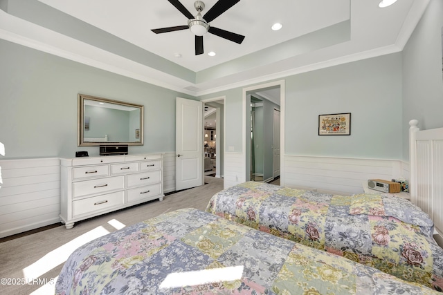 carpeted bedroom with crown molding, ceiling fan, and a raised ceiling