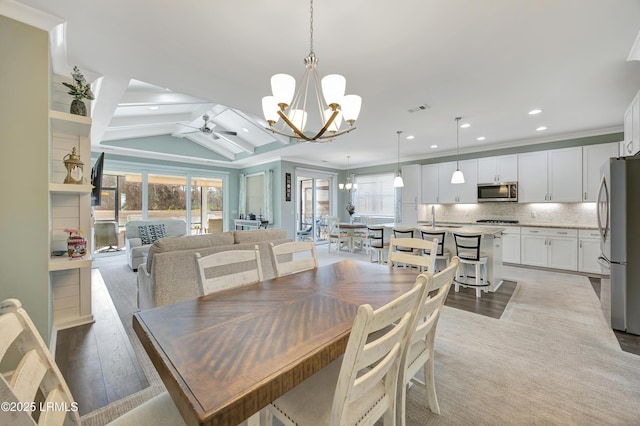 dining room featuring lofted ceiling, sink, ornamental molding, light hardwood / wood-style floors, and ceiling fan with notable chandelier