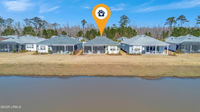 back of property featuring a water view, a sunroom, and a lawn