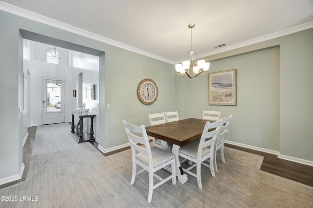 dining area featuring an inviting chandelier, ornamental molding, and light hardwood / wood-style floors