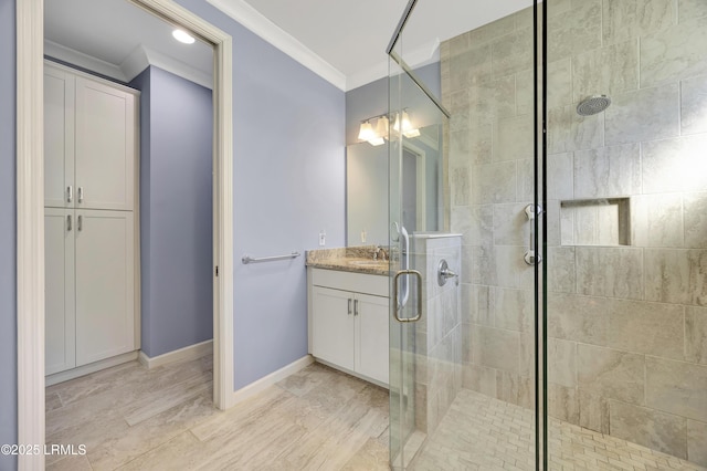 bathroom with crown molding, vanity, and a shower with shower door