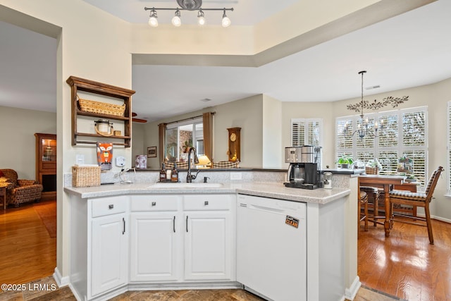 kitchen with sink, white cabinetry, light wood-type flooring, dishwasher, and pendant lighting