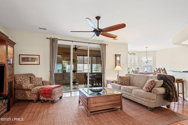 living room with hardwood / wood-style flooring and ceiling fan with notable chandelier