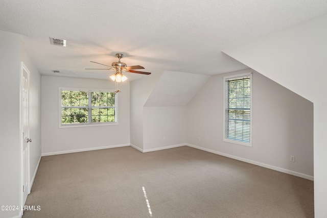 bonus room featuring vaulted ceiling, carpet flooring, ceiling fan, and a textured ceiling