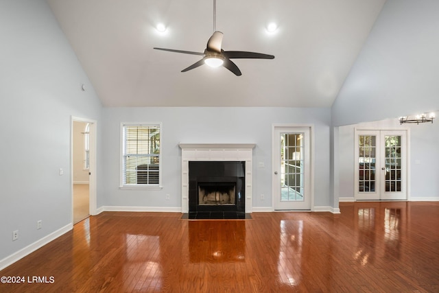 unfurnished living room featuring ceiling fan, high vaulted ceiling, a fireplace, wood-type flooring, and french doors