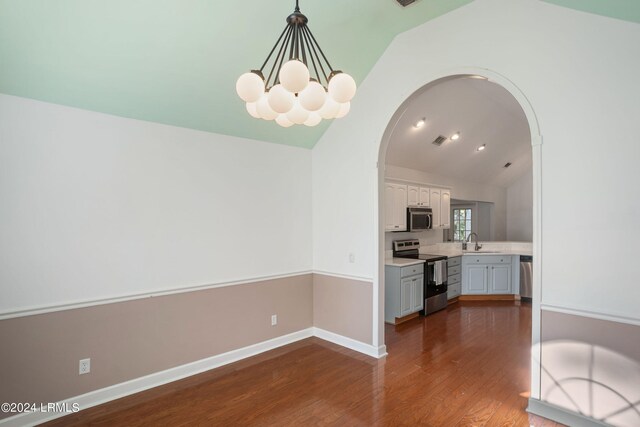 kitchen with sink, hanging light fixtures, stainless steel appliances, white cabinets, and vaulted ceiling