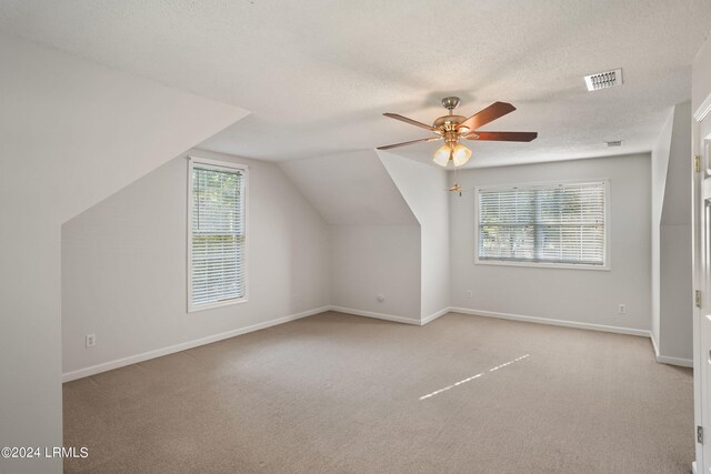 bonus room with lofted ceiling, light colored carpet, a textured ceiling, and ceiling fan