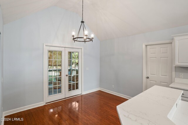 unfurnished dining area featuring vaulted ceiling, dark hardwood / wood-style floors, a chandelier, and french doors