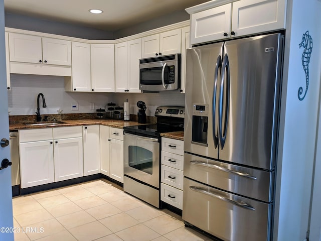 kitchen with backsplash, white cabinets, stainless steel appliances, and a sink