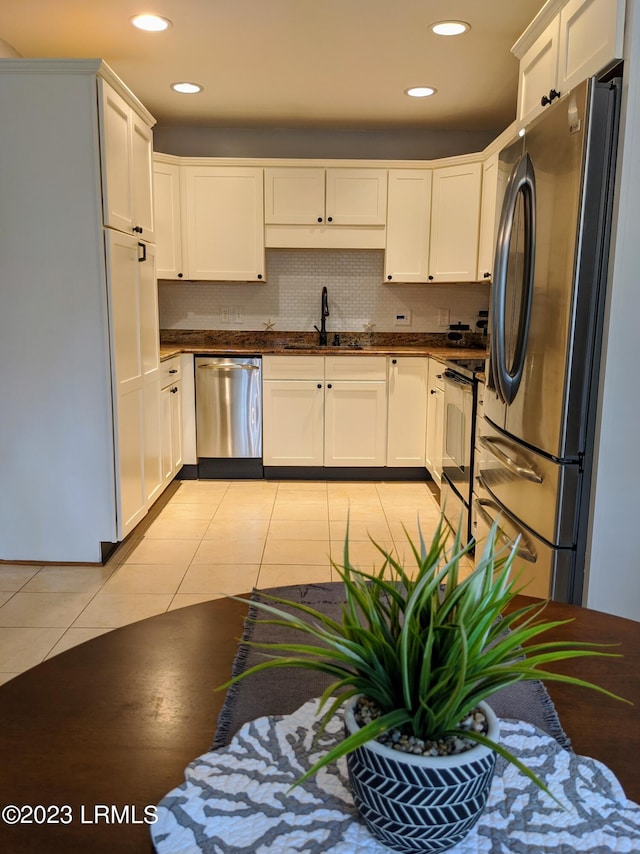 kitchen featuring a sink, dark countertops, appliances with stainless steel finishes, and light tile patterned floors