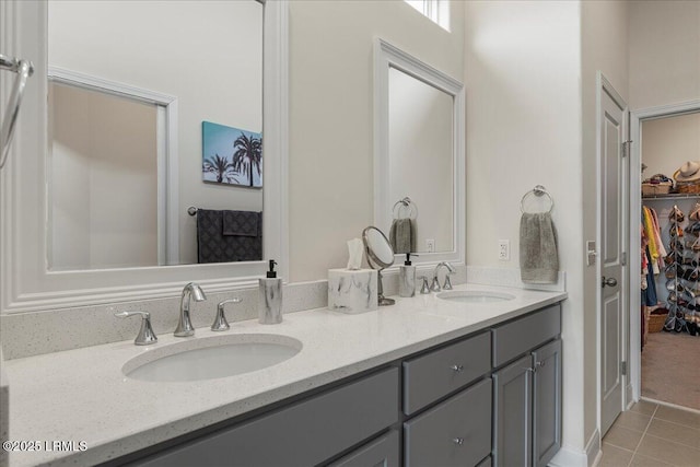 bathroom with tile patterned flooring, a sink, a spacious closet, and double vanity