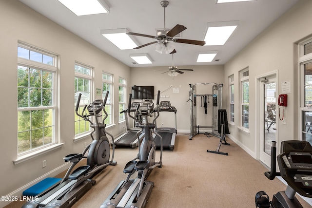 workout room with a skylight, ceiling fan, and baseboards