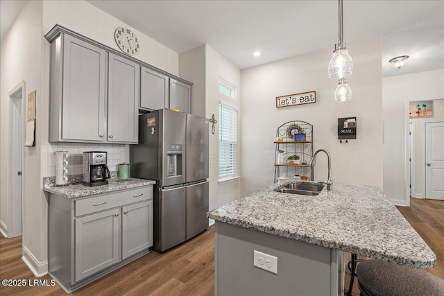 kitchen with sink, stainless steel fridge, light stone countertops, and gray cabinets