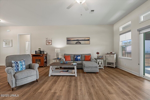 living room featuring baseboards, visible vents, ceiling fan, and wood finished floors