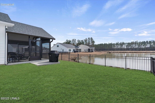 view of yard featuring a water view, a fenced backyard, and a sunroom