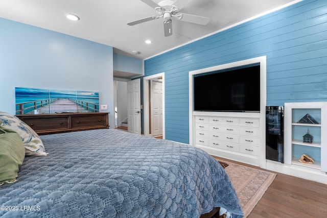 bedroom featuring wood walls, a ceiling fan, wood finished floors, and recessed lighting