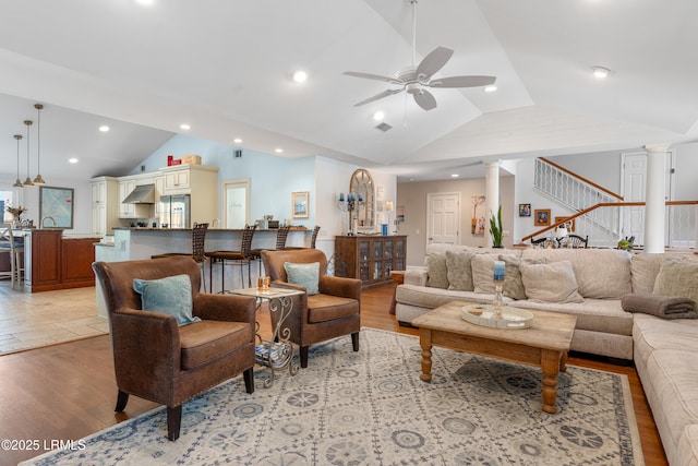 living room with decorative columns, lofted ceiling, recessed lighting, light wood-style flooring, and a ceiling fan