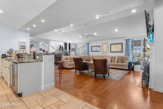 kitchen featuring lofted ceiling, a breakfast bar, dark stone countertops, a sink, and recessed lighting