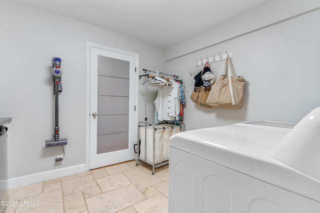 laundry room with laundry area, independent washer and dryer, stone tile flooring, and baseboards