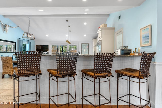 kitchen with vaulted ceiling with beams, a breakfast bar area, decorative light fixtures, and recessed lighting