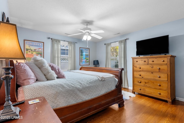 bedroom with a textured ceiling, wood finished floors, and baseboards