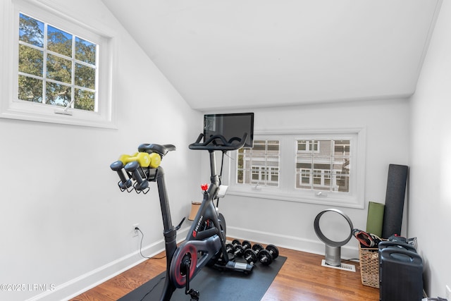 workout area with visible vents, vaulted ceiling, baseboards, and wood finished floors