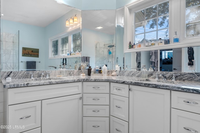 bathroom featuring a stall shower, a sink, and double vanity