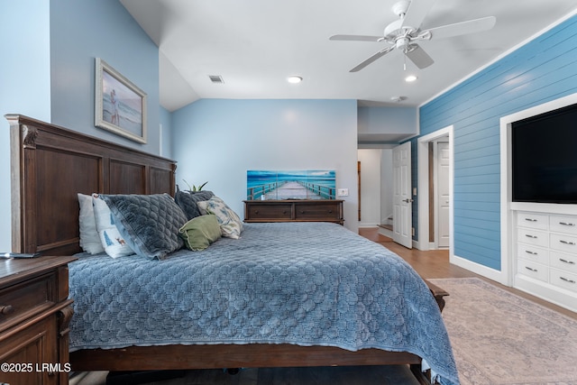 bedroom featuring visible vents, a ceiling fan, lofted ceiling, wood finished floors, and wood walls