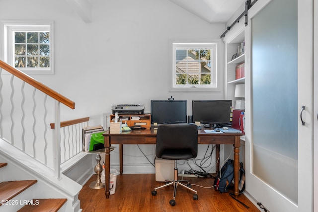 office with lofted ceiling, a barn door, plenty of natural light, and wood finished floors