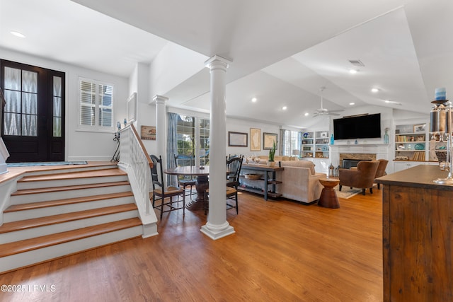 entryway featuring lofted ceiling, ornate columns, light wood-style flooring, and stairs