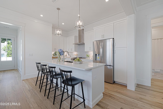 420 Waight St, Beaufort, SC 29902 - kitchen featuring stainless steel fridge with ice dispenser, wall chimney exhaust hood, a kitchen island with sink, light countertops, and light wood-type flooring