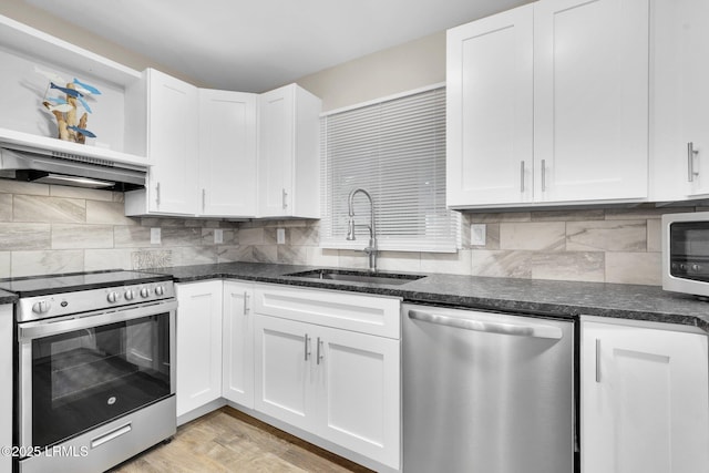 kitchen featuring sink, appliances with stainless steel finishes, white cabinets, light hardwood / wood-style floors, and backsplash